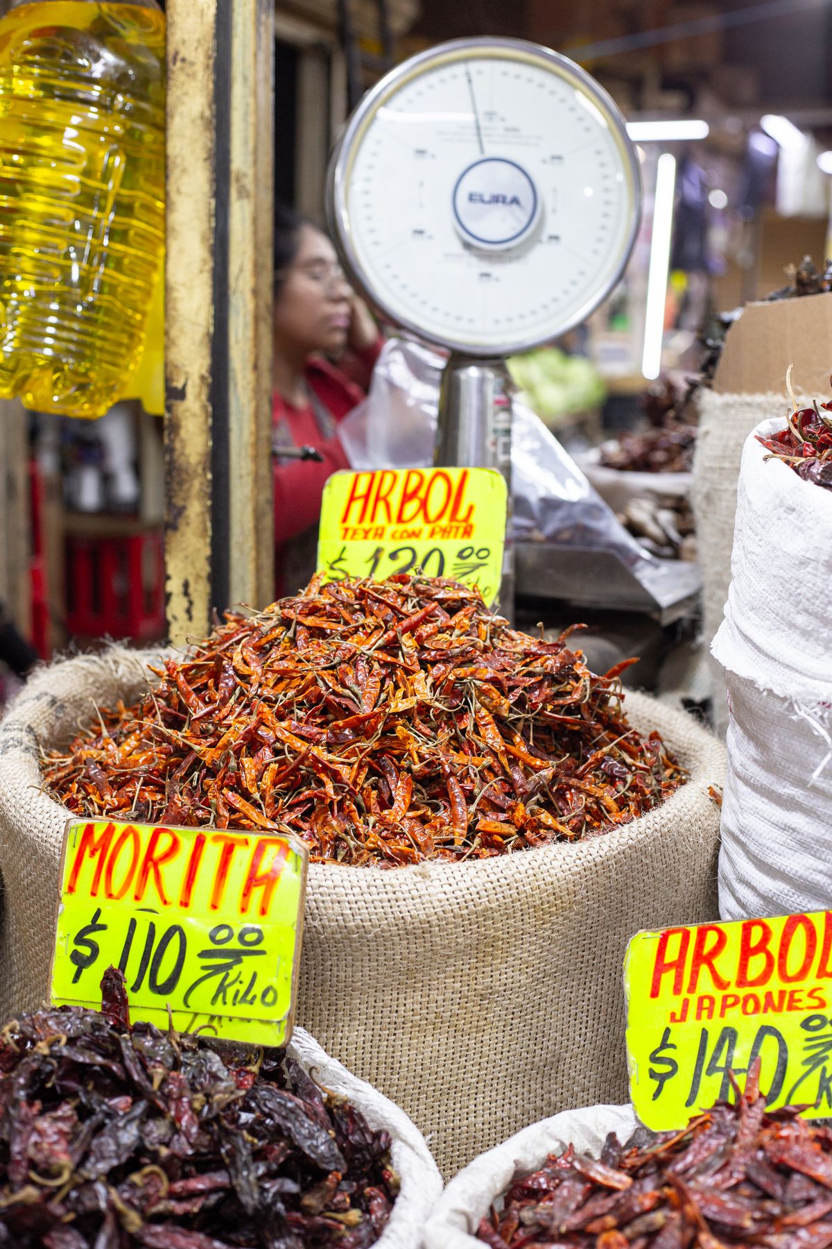 Puesto de chiles secos a granel con costales y etiquetas de precio