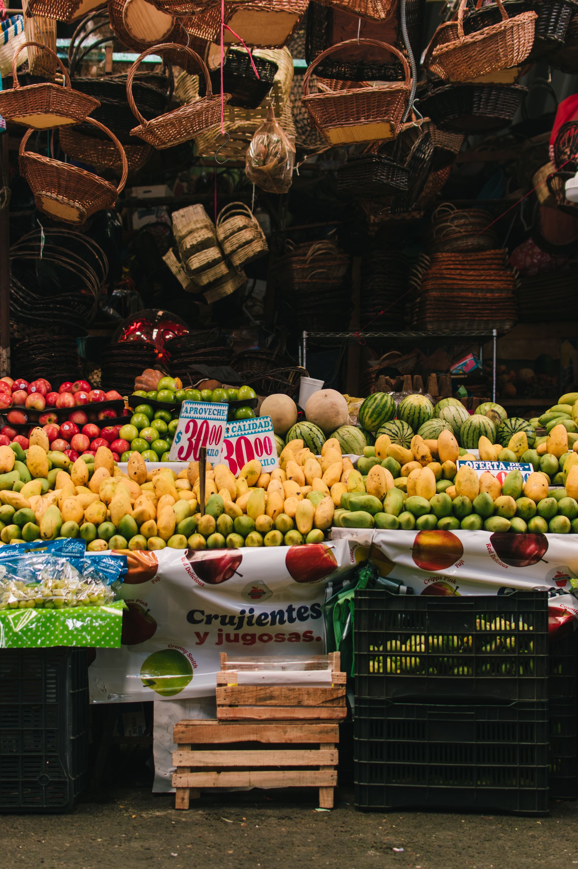 Puesto de frutas y verduras con cajas apiladas en un mercado de la Ciudad de México